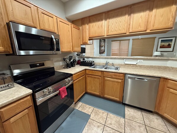 A modern kitchen with wooden cabinets, stainless steel appliances, a double sink, and a dishwasher.