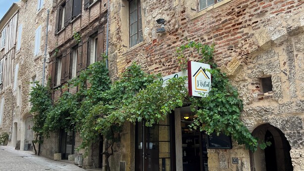 Un edificio histórico con fachada de piedra, un letrero de restaurante y una calle adoquinada.