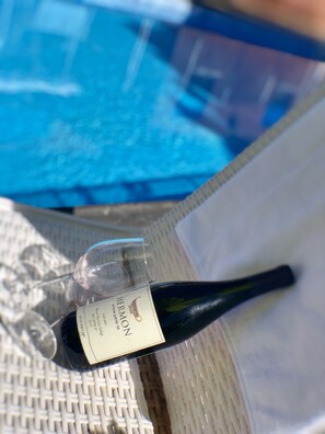 A bottle of Hermon Z wine with a label, placed on a white woven surface near a pool. - Zimmer Cigale (Odem)