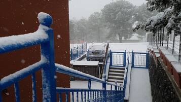 A snow-covered outdoor staircase leading to a building with a red wall and blue railings.