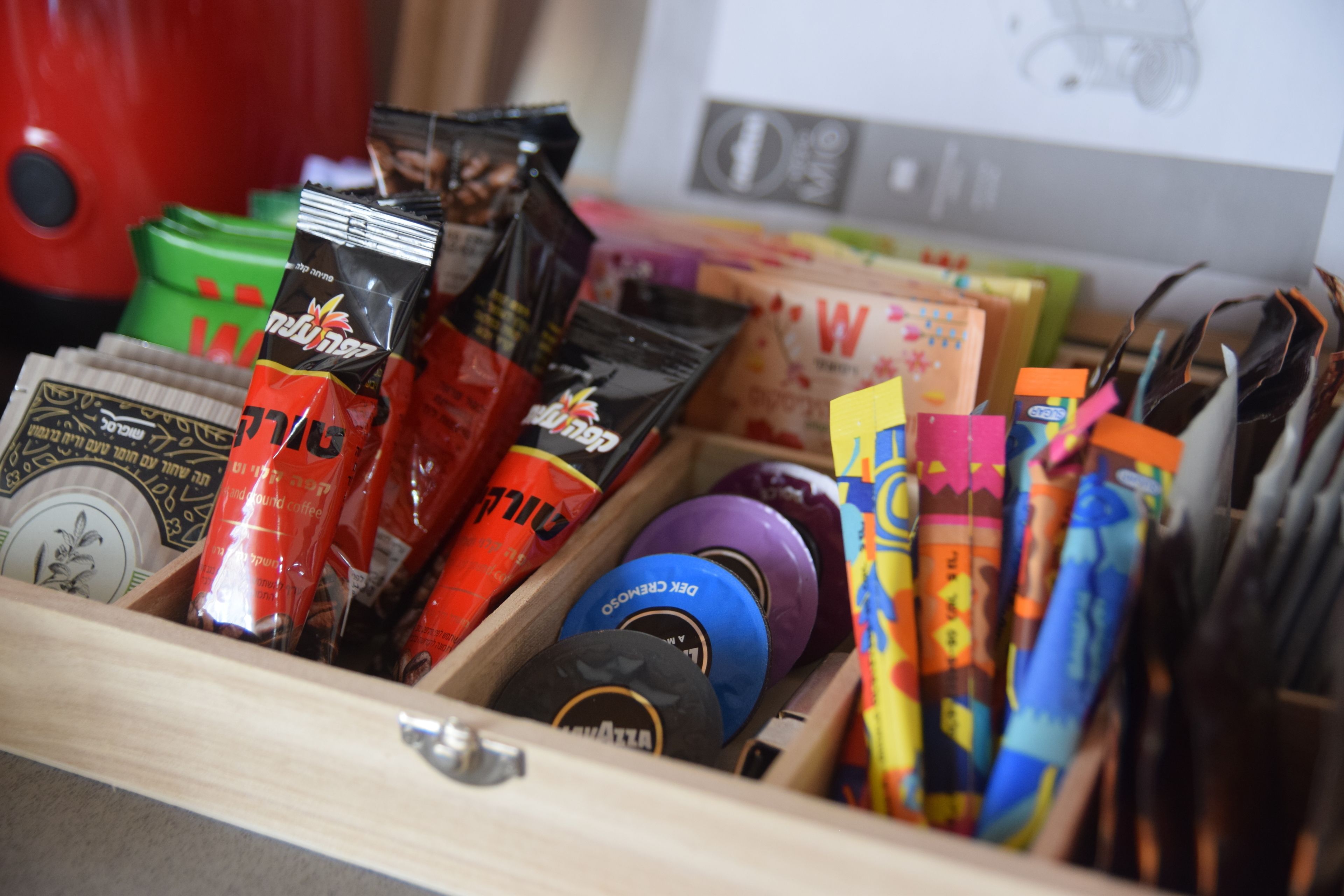 A drawer containing various items including coffee packets, a blue container, and colorful stationery.