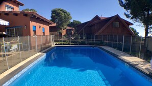Una piscina rectangular con agua azul cristalina, rodeada por una barandilla de vidrio.