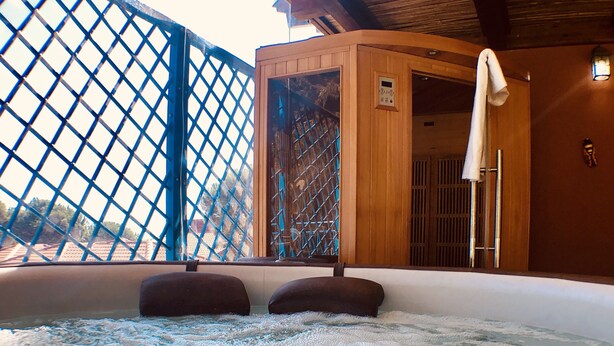 Un jacuzzi con cerramiento de madera, cerca metálica y una toalla colgada en un perchero.