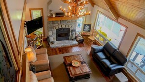 A cozy living room with a stone fireplace, leather sofas, and a wooden coffee table.
