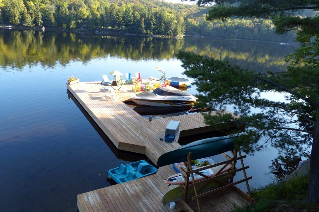 A wooden dock extending into a calm lake surrounded by trees.