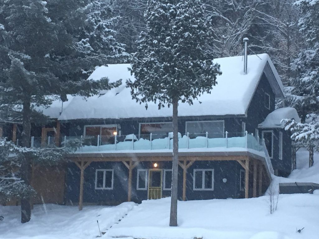 Eine schneebedeckte Lodge mit einer großen Veranda und zahlreichen Fenstern.