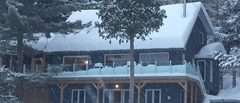 Eine schneebedeckte Lodge mit einer großen Veranda und zahlreichen Fenstern.