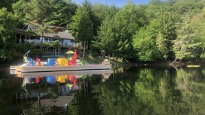 A lakeside dock with colorful chairs and umbrellas, surrounded by dense forest.