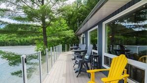 A wooden deck with outdoor seating, overlooking a body of water.