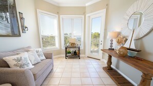 A cozy living room with a beige sofa, a wooden console table, and a large mirror. - Beach & Bay views! 4BR/3.5BA, Elevator, Com Pool/Tennis Court (St. George Island)