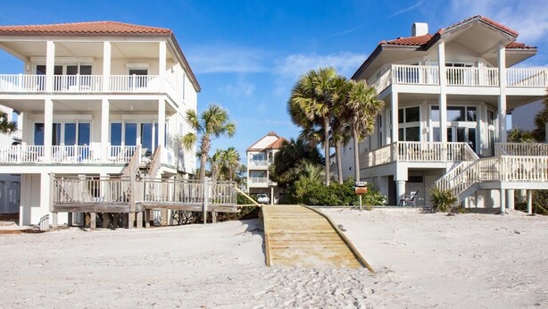 A beachfront property with a wooden walkway leading to a white building with balconies. - Beach & Bay views! 4BR/3.5BA, Elevator, Com Pool/Tennis Court (St. George Island)