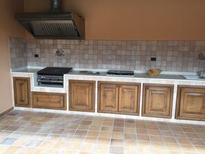 Kitchen features a gas stove and range hood, along with a tiled backsplash and wooden cabinets.