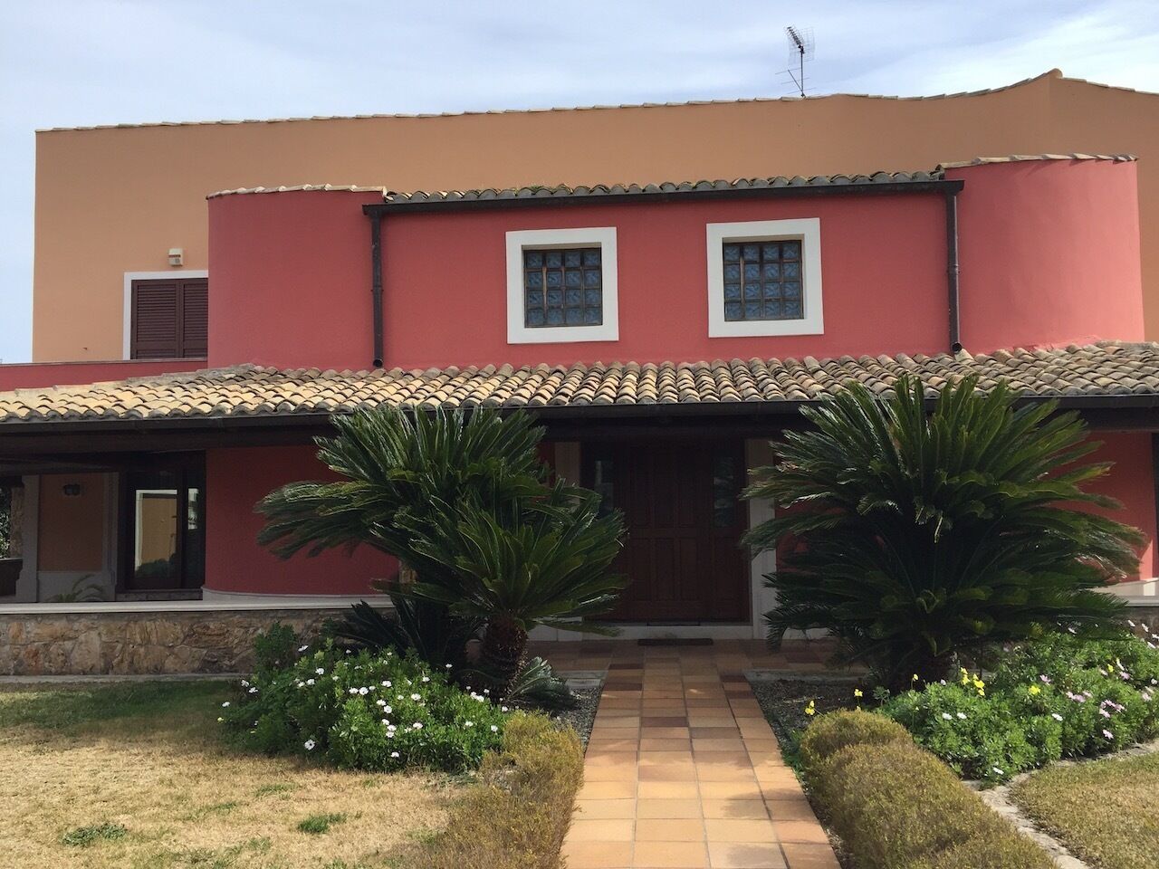 A two-story building with a red facade, a tiled roof, and a central entrance.
