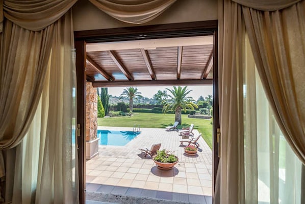 Step outside to a patio with a pool, lounge chairs, and a dining table.