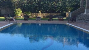 A swimming pool with a stone wall and chairs around it. - Luxurious villa Maremonti (Canicattini Bagni)