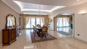 A spacious dining area with a chandelier, a wooden dining table, and chairs. - Luxurious villa Maremonti (Canicattini Bagni)