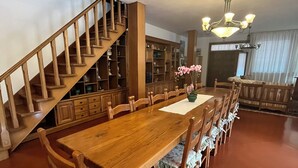 Ein geräumiger Essbereich mit einem langen Holztisch und Stühlen, einer Treppe und einer Bibliothek mit Holzbögen.