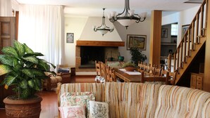 Ein Wohnzimmer mit einer Couch, Stühlen, einem Esstisch, einem Kamin und einer Treppe.
