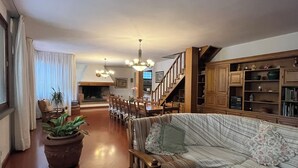 Ein geräumiges Wohnzimmer mit einer Couch, einem Esstisch und Stühlen. Eine Treppe führt zu einer oberen Ebene.