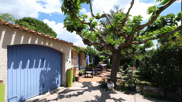 A courtyard with a blue garage door, potted plants, and outdoor furniture. - Vacation rental house with pool MOURIES LS1-308 (Mouri ès)