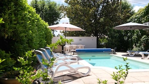 A pool area with lounge chairs and umbrellas, surrounded by greenery. - Vacation rental house with pool MOURIES LS1-308 (Mouriès)