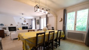 A dining area with a table set for six, a fireplace, a television, and a window with curtains. - Vacation rental house with pool MOURIES LS1-308 (Mouriès)