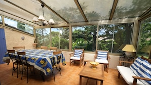 A sunroom with a table and chairs, large windows, and a view of the outdoors. - Vacation rental house with pool MOURIES LS1-308 (Mouriès)