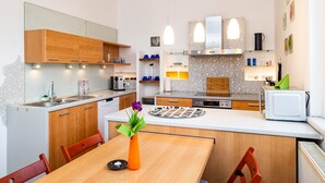 A modern kitchen with wooden cabinets, a white countertop, and pendant lights.