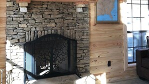 Ein Kamin aus Stein mit einem Fernseher darüber, eine Karte an der Wand und ein Fenster mit Blick.