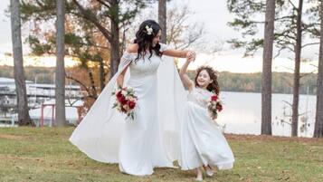 A wedding scene with a bride and two flower girls by a lake.