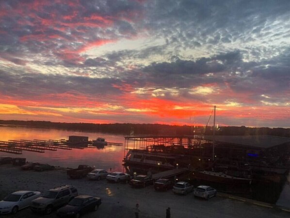 Une vue sur le front de mer, avec un coucher de soleil, des bateaux amarrés et un bâtiment doté d’une zone abritée.