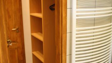 Un baño con puerta de madera, radiador blanco y suelo de baldosas.