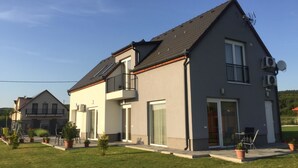 A modern two-story house with a grey facade, large windows, and a balcony. - Szabolcs Apartments (Demjén)