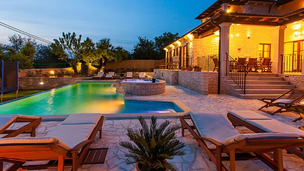 A pool area with lounge chairs, a hot tub, and a covered patio with outdoor seating.