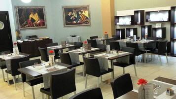 Una sala ristorante con tavoli apparecchiati, sedie e opere d'arte alle pareti.