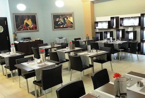 A restaurant with tables set for dining, chairs, and artwork on the walls. - La Bussola Hotel (Milazzo)