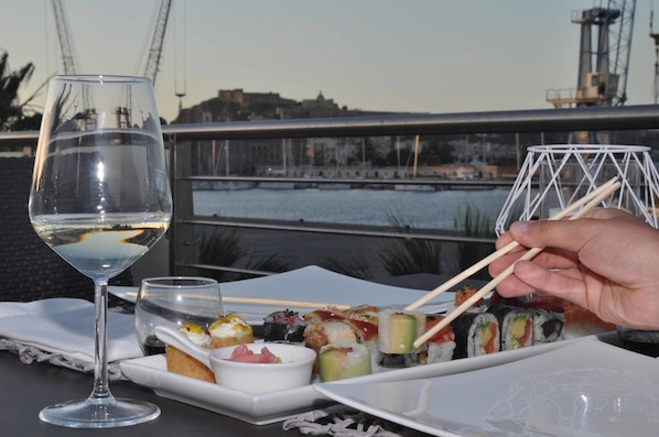 A table with sushi, a glass of white wine, and chopsticks. - La Bussola Hotel (Milazzo)