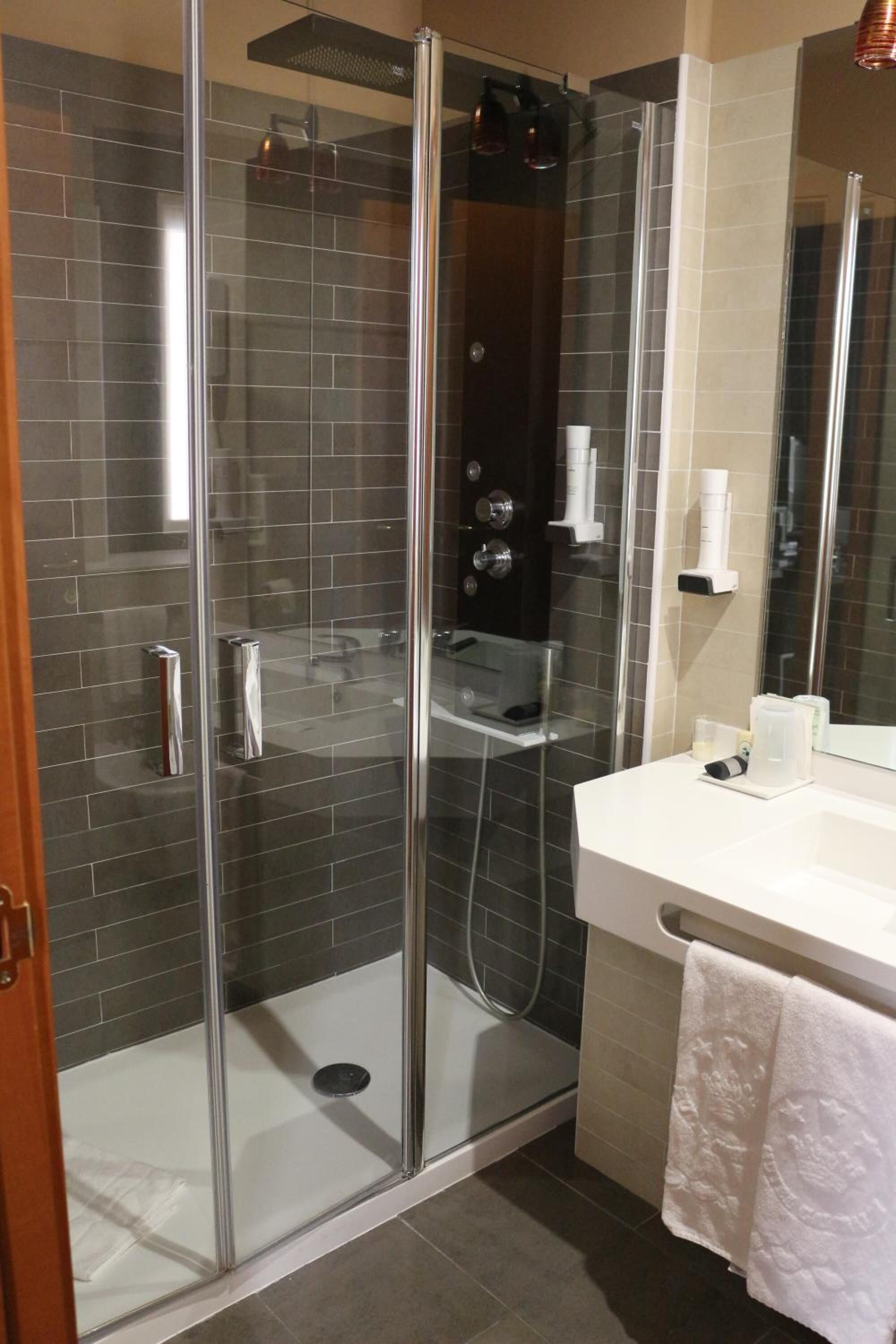 A glass-enclosed shower with a white sink and a towel rack.