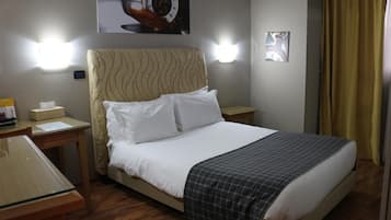 A hotel room with a bed, bedside tables, a desk, and a wall clock.