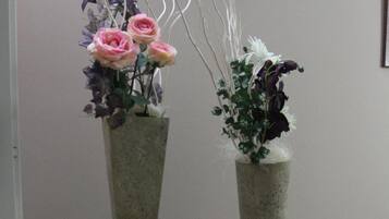 Dos jarrones con flores sobre soportes metálicos frente a una pared.