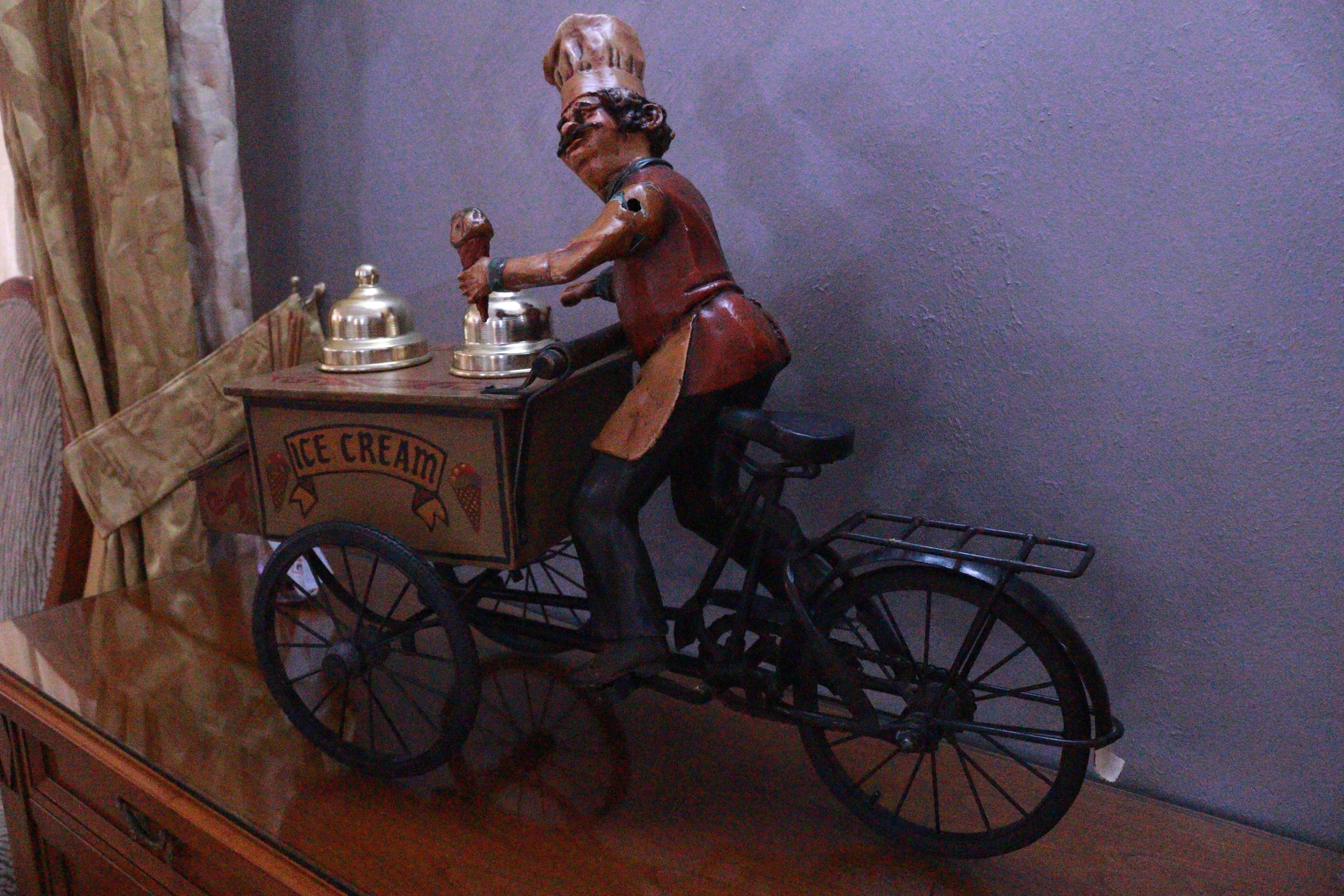 A vintage ice cream vendor figurine on a wooden table.