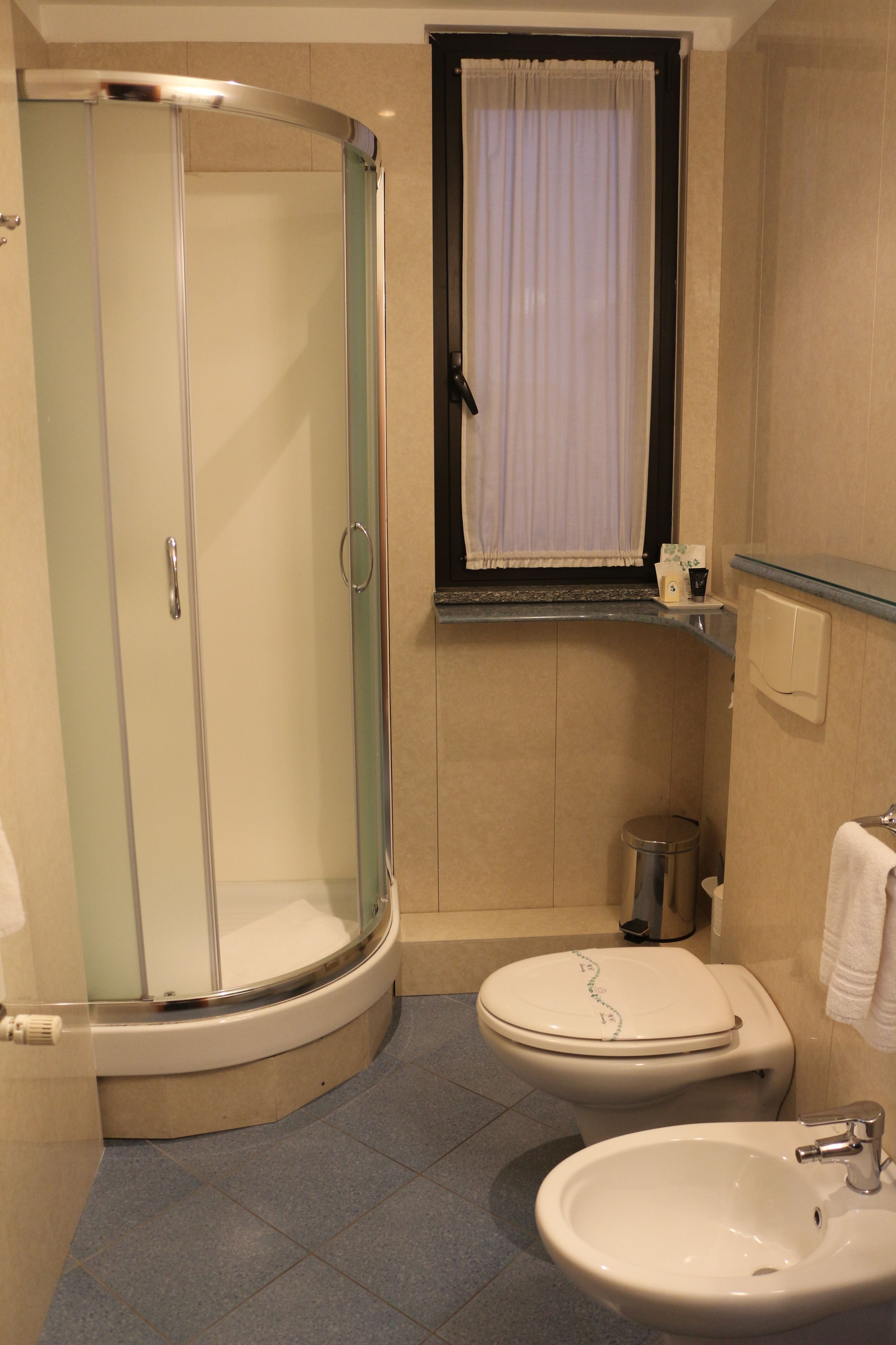 A bathroom with a glass-enclosed shower, a toilet, and a sink.