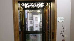 Un ascensor de diseño moderno, con indicador de planta visible y un elemento decorativo en la pared.