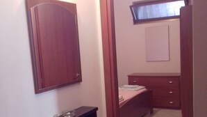 A bedroom with a bed, a bedside table, and a wardrobe. - Appartamenti a Pochi Passi dal Mare (Marsala)