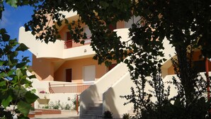 A multi-story building with a central staircase, surrounded by greenery. - Appartamenti a Pochi Passi dal Mare (Marsala)