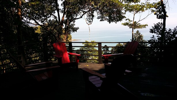 Une terrasse avec des chaises rouges et vue sur la mer.