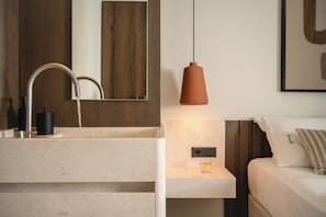 A modern bathroom with a marble sink, a mirror, a pendant light, and a bedside table with a glass. - Espera Beachfront Residence, Coastal City Living (Rethymno)