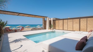 Un espace piscine avec vue sur la mer, des chaises longues et des parasols.
