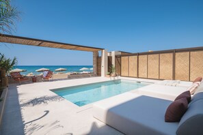 A pool area with a view of the sea, lounge chairs, and umbrellas. - Espera Beachfront Residence, Coastal City Living (Rethymno)