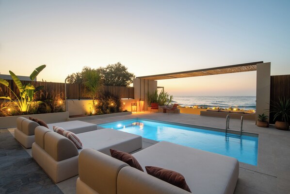 Un espace aménagé au bord de la piscine, avec des chaises longues et une vue sur l’océan.